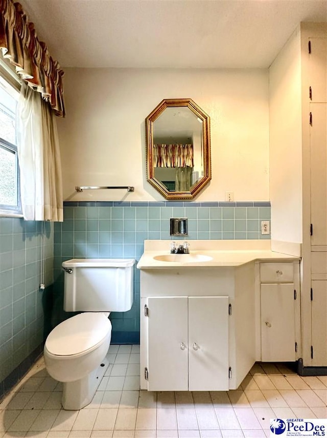 bathroom with vanity, tile patterned floors, tile walls, and toilet