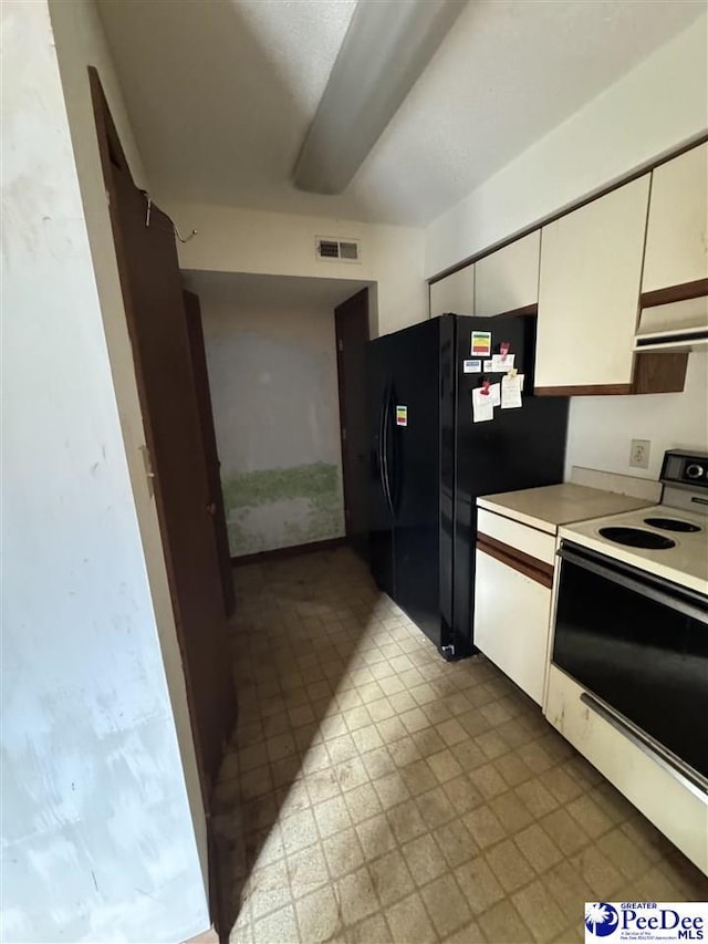 kitchen with ventilation hood, visible vents, white range with electric cooktop, freestanding refrigerator, and white cabinetry