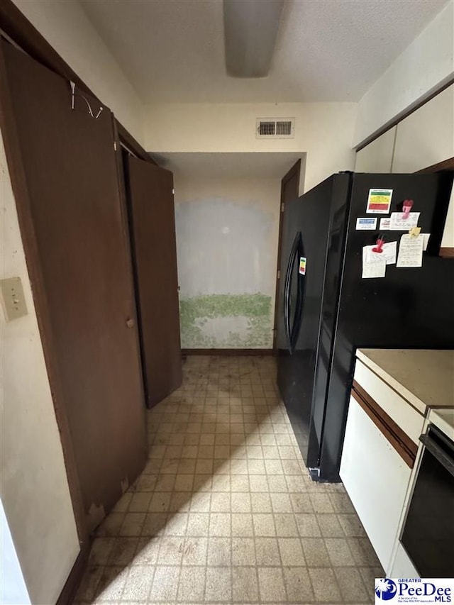 kitchen with visible vents, freestanding refrigerator, light countertops, range, and light floors