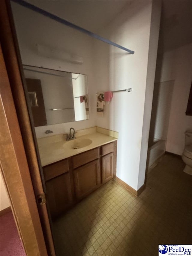 bathroom with vanity, baseboards, a shower, tile patterned floors, and toilet