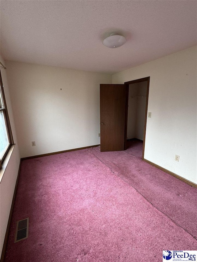 spare room featuring carpet flooring, baseboards, visible vents, and a textured ceiling