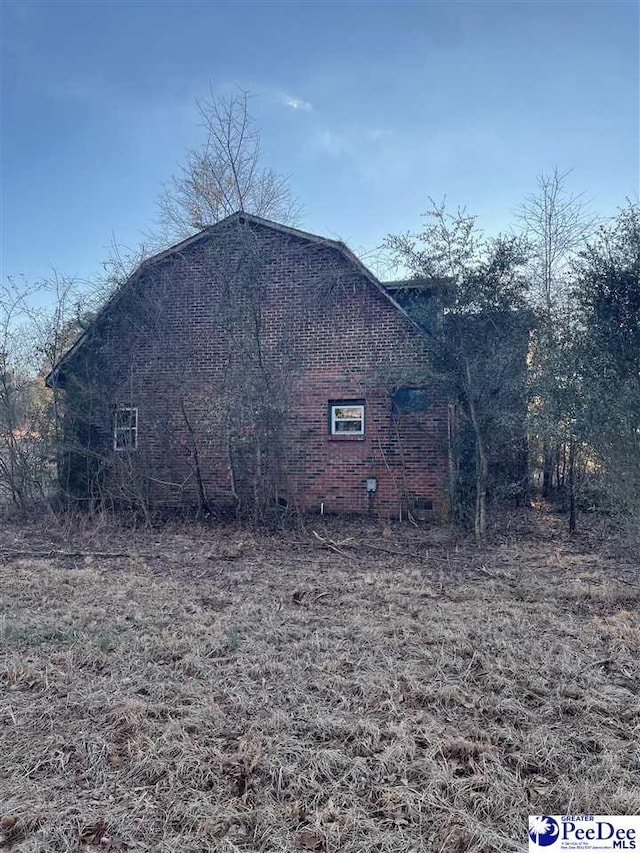 view of side of property featuring crawl space, a barn, and brick siding