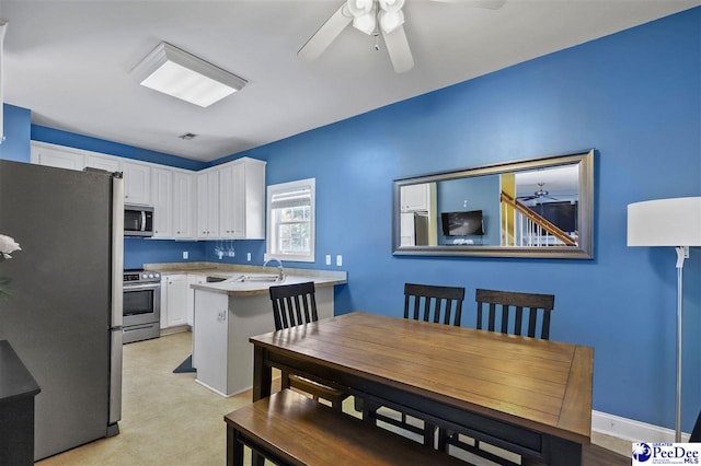 kitchen with a peninsula, white cabinetry, light countertops, appliances with stainless steel finishes, and light floors