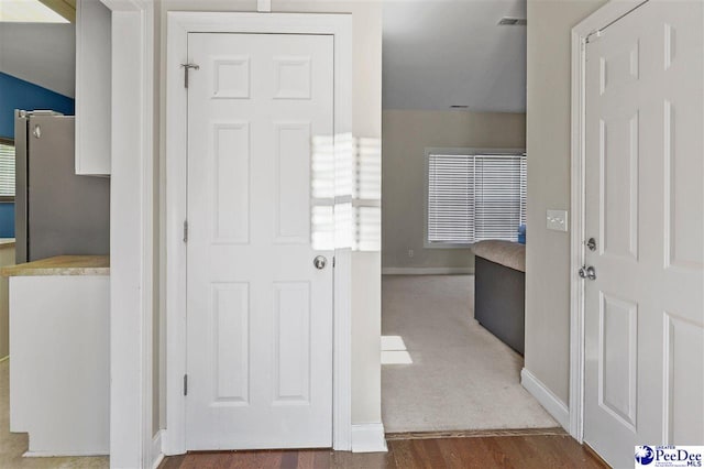 corridor featuring visible vents, baseboards, and wood finished floors