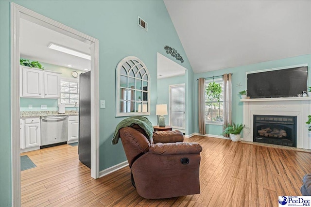 living room featuring baseboards, visible vents, a fireplace, and light wood finished floors