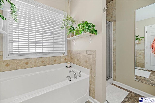 full bathroom featuring a stall shower, baseboards, and a bath