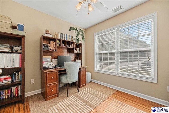 office area with a ceiling fan, wood finished floors, visible vents, and baseboards