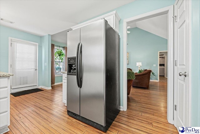 kitchen with stainless steel fridge, visible vents, light wood finished floors, and white cabinetry