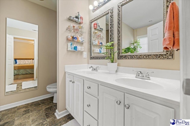 full bath with toilet, double vanity, a sink, and ensuite bathroom