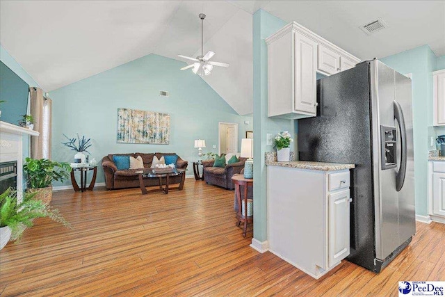 kitchen with visible vents, white cabinets, open floor plan, light countertops, and stainless steel refrigerator with ice dispenser