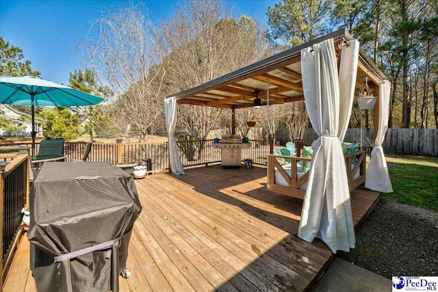 deck featuring ceiling fan, fence, a grill, and outdoor dining space