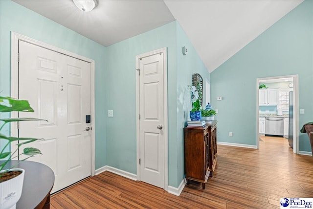 foyer featuring vaulted ceiling, wood finished floors, and baseboards