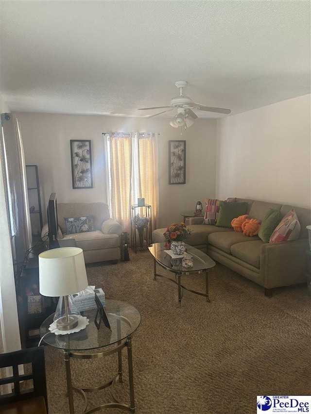 living room with a textured ceiling, ceiling fan, and dark colored carpet