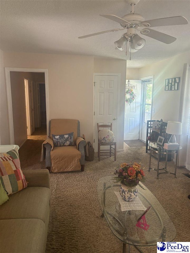 carpeted living room featuring ceiling fan and a textured ceiling