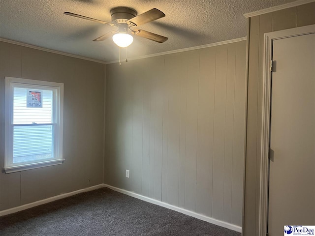 spare room with a textured ceiling, ceiling fan, dark carpet, and ornamental molding