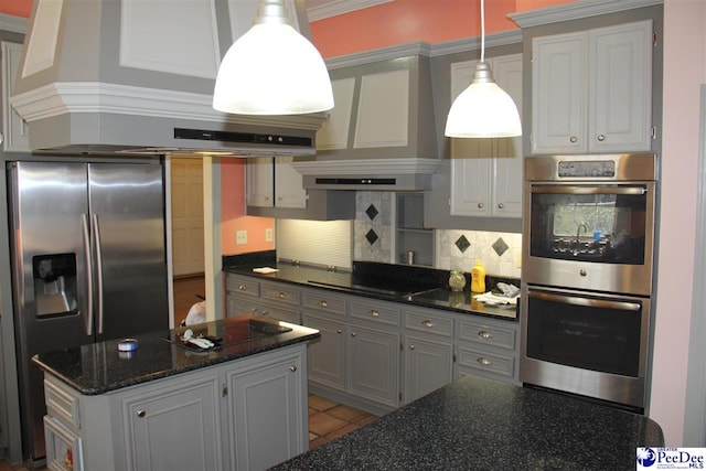 kitchen featuring wall chimney exhaust hood, dark stone countertops, pendant lighting, stainless steel appliances, and backsplash