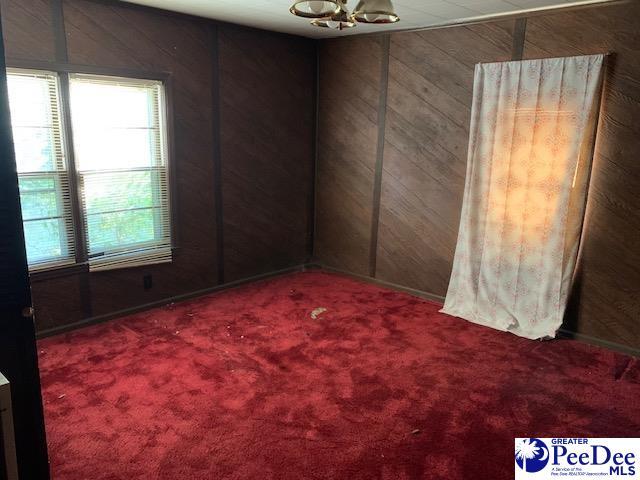 carpeted empty room with a notable chandelier