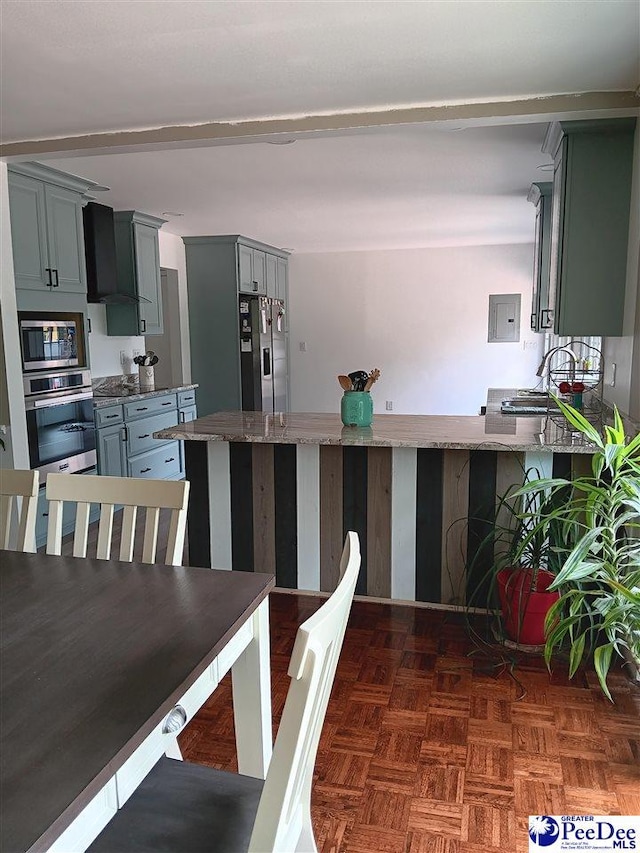 kitchen featuring appliances with stainless steel finishes, electric panel, dark parquet floors, kitchen peninsula, and wall chimney exhaust hood