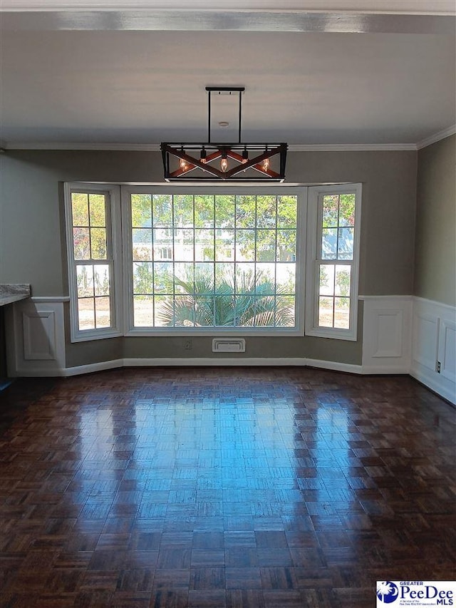 unfurnished dining area featuring dark parquet flooring, plenty of natural light, and crown molding