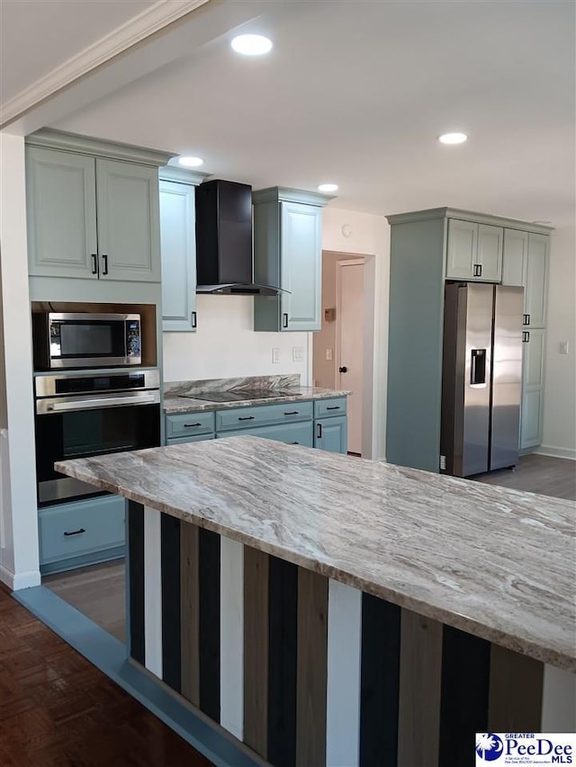 kitchen featuring wall chimney exhaust hood, appliances with stainless steel finishes, and light stone countertops