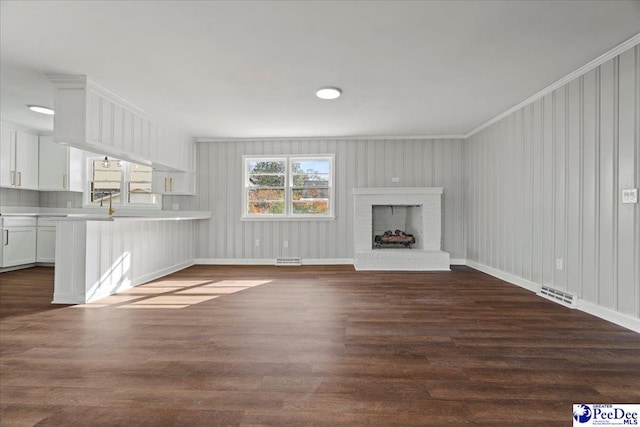 unfurnished living room with a fireplace, ornamental molding, and dark hardwood / wood-style floors