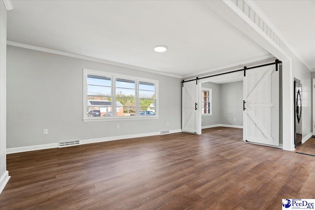 unfurnished living room with ornamental molding, a barn door, and dark hardwood / wood-style floors