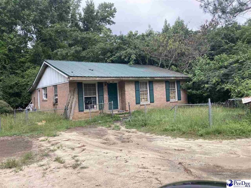 514 Bea Ct, Dillon, SC 29536 - ranch-style house featuring brick siding, covered porch, a metal roof, and driveway