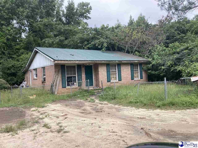 514 Bea Ct, Dillon, SC 29536 - ranch-style house featuring brick siding, covered porch, a metal roof, and driveway