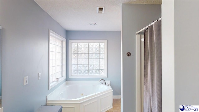 bathroom featuring a textured ceiling, a shower with shower curtain, baseboards, visible vents, and a garden tub