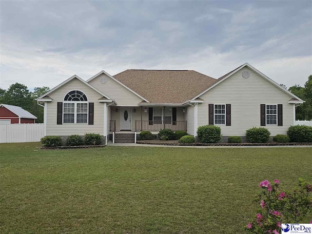 ranch-style house with a front yard, covered porch, and fence