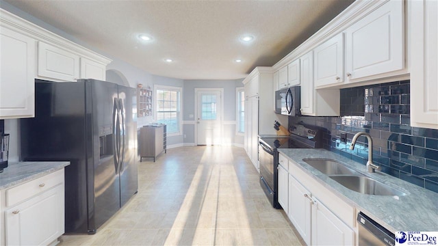 kitchen featuring recessed lighting, black appliances, decorative backsplash, and a sink