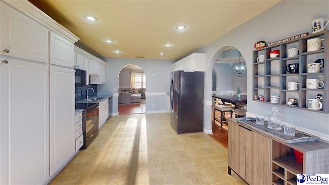 kitchen with white cabinetry, a sink, arched walkways, black appliances, and recessed lighting