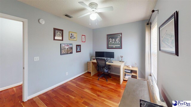 home office with a wealth of natural light, visible vents, light wood-type flooring, and a ceiling fan