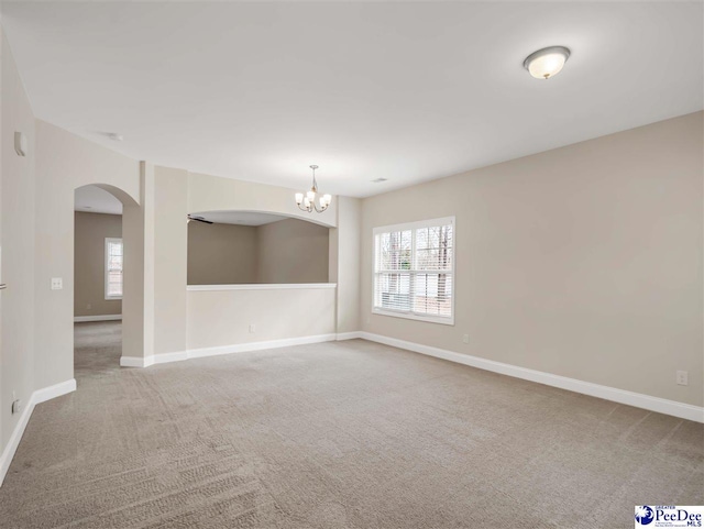 carpeted empty room featuring a notable chandelier