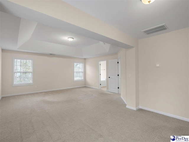 unfurnished room with a tray ceiling and light colored carpet