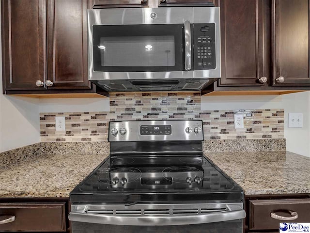 kitchen featuring decorative backsplash, dark brown cabinets, light stone countertops, and appliances with stainless steel finishes