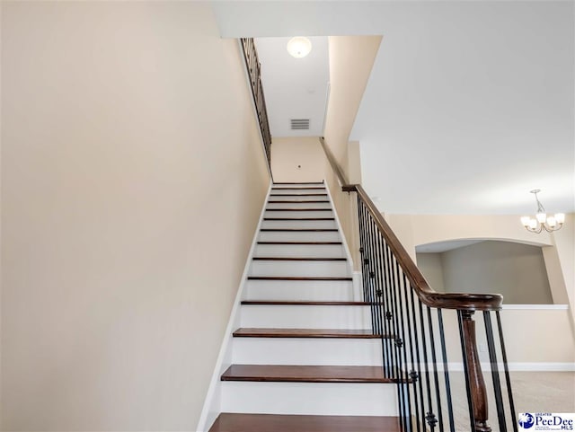 stairs featuring an inviting chandelier