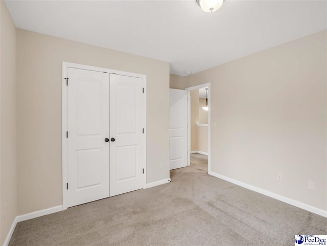 unfurnished bedroom with light colored carpet and a closet