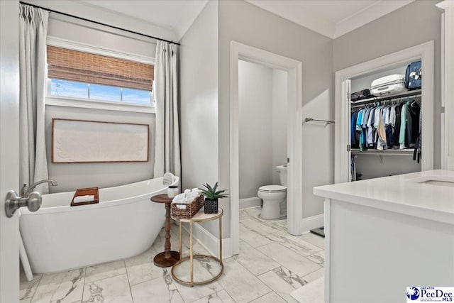 full bathroom with baseboards, marble finish floor, toilet, vanity, and a freestanding bath