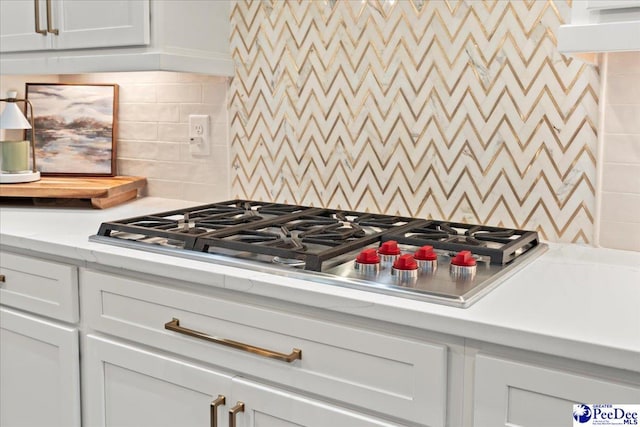 kitchen featuring white cabinetry, light stone countertops, stainless steel gas stovetop, and decorative backsplash