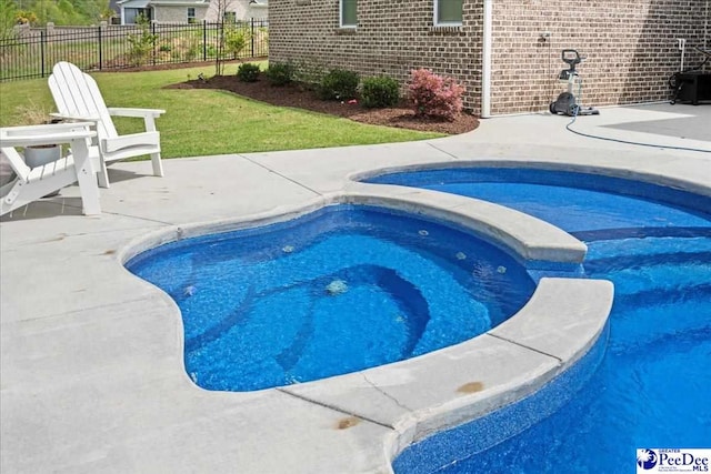 view of pool with a pool with connected hot tub, fence, and a patio area