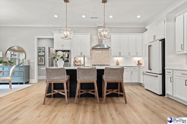 kitchen featuring a kitchen breakfast bar, light countertops, stainless steel appliances, backsplash, and wall chimney range hood