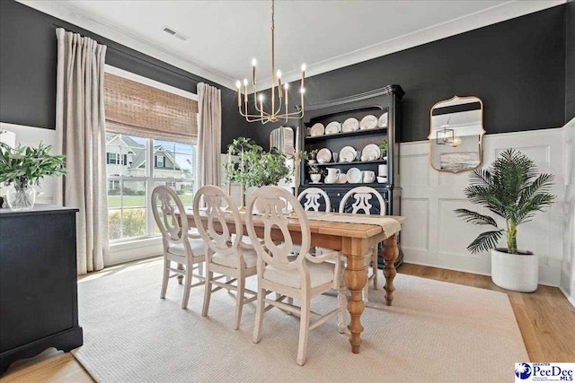 dining room featuring light wood-type flooring, a notable chandelier, crown molding, and visible vents
