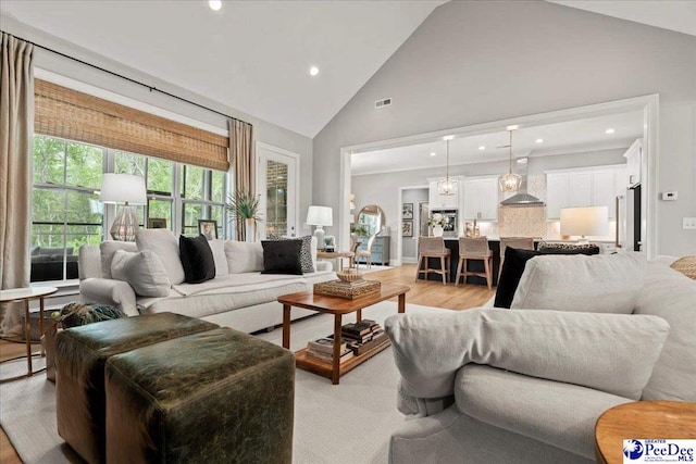 living area with recessed lighting, high vaulted ceiling, light wood-style floors, and visible vents
