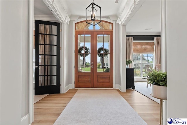 foyer featuring french doors, ornamental molding, baseboards, and wood finished floors