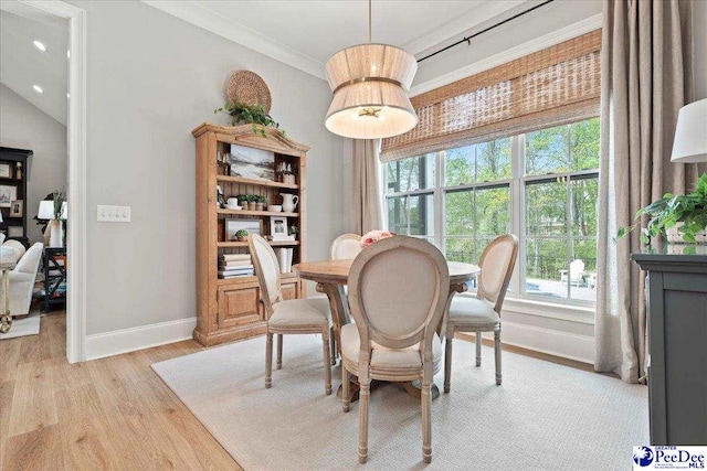 dining area featuring baseboards, light wood-style flooring, and crown molding