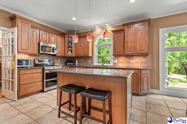 3250 Hampton Pointe Dr, Florence, SC 29501 - kitchen with stainless steel appliances, a center island, a breakfast bar area, decorative backsplash, and brown cabinets