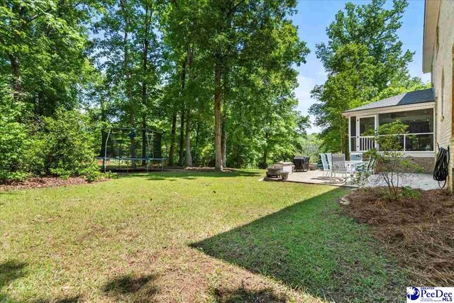 3250 Hampton Pointe Dr, Florence, SC 29501 - view of green lawn with a trampoline, a patio area, and a sunroom