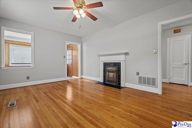 1306 W Palmetto St, Florence, SC 29501 - unfurnished living room featuring a tiled fireplace, light wood-type flooring, plenty of natural light, and a ceiling fan