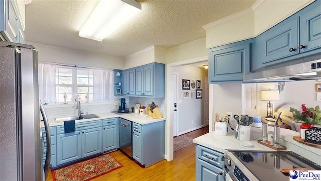 kitchen with sink, light hardwood / wood-style flooring, blue cabinetry, stainless steel appliances, and a textured ceiling